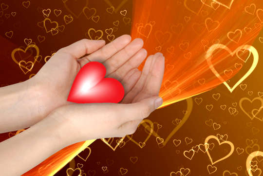 Today's Inspiration: December 25, 2022 hands holding out a glowing heart with a background of a myriad of hearts