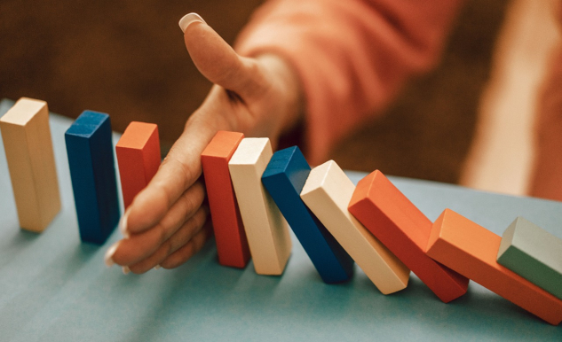 Dominos starting to tumble with a hand stopping them.&nbsp;Image by Oleksandr Pidvalnyi from Pixabay.&nbsp;